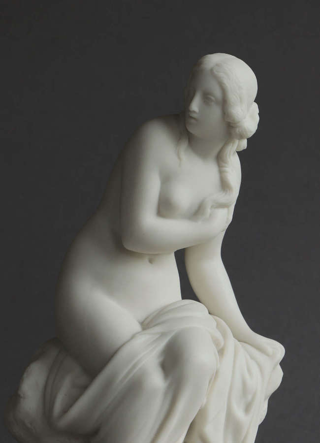A small Goss Parian figure of a bather seated on a rock